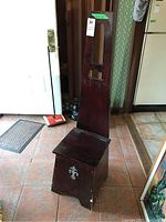 Tall wood hallway bench with high back and seat lifted, revealing storage space. Shows scratches and wear.