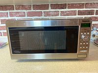 Front view of the Panasonic microwave showing door, handle, and control panel with display and buttons.