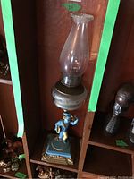 Full view of the oil lamp with glass chimney and painted metal newspaper boy base.