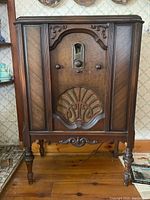 Full view of Philco vintage radio cabinet showing wood cabinet with ornate carved details, four legs, and front speaker grille design.