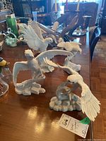 Four white porcelain bird figurines arranged on tabletop, clearly showing detailed feather work and varied bird poses.