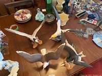 Four porcelain bird figurines by Franklin Porcelain on table showing different flying and perched poses, with detailed painting and bases.