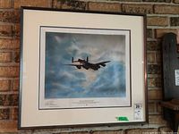 Framed print of a World War II bomber aircraft flying in cloudy sky, signed and numbered edition.