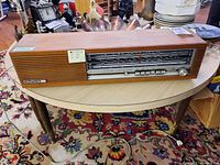 Front view of vintage Nordmende radio on a wooden table, showing the full length with tuning display and speaker grille.
