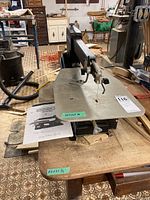 Front view of saw on wooden table with operator manual at base