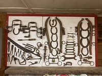 Mounted board displaying various vintage hand tools including hand drills, wrenches, horse hames, horseshoes.