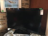 Front view of the LG 42LV4400-UA TV showing screen and stand with remote on lace cloth.