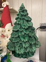Front view of the green glazed ceramic Christmas tree showing detailed leaf design and holes for bulbs.