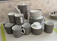 Complete set with mugs, plates, bowls, coffee pot, sugar bowl, and creamer arranged on table.