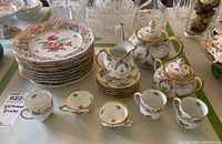 Overhead view showing six luncheon plates stacked, four espresso cups, two coffee cups, creamer, sugar bowl, teapot