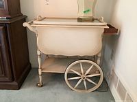 Full view of the cream painted solid walnut tea cart with large spoked wooden wheels and removable tray on top.