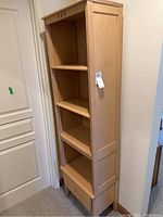 Full view of a light wood bookshelf showing four open compartments and bottom drawer.