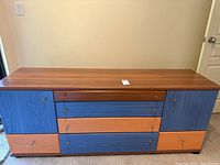 Front view of the storage cabinet showing colorful drawers and doors with different wood-tone laminate finishes.