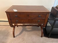 Front view showing two drawers, metal knobs, rectangular table top with some surface scratches.