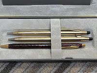 Three gold-filled Élysée ballpoint pens displayed in velvet-lined case