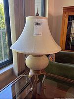 Full view of the metal and ceramic table lamp showing the fabric shade and decorative metal base.