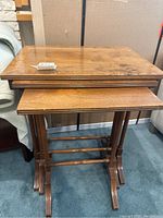 Photo showing three wooden nesting tables stacked, highlighting water stains on top surfaces.