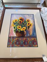 Full view of the framed flower painting depicting sunflowers in a vase on a patterned cloth.