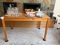 Full view of the pine wooden table showing overall shape and surface with items on top (not included)