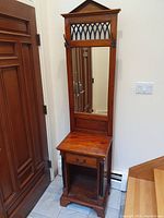 Full view of the hall stand showing the tall mirror with lattice top, drawer, and open storage area at the base.