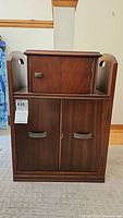 Full front view of vintage wooden stand with small top compartment and two cabinet doors below, showing size and design