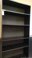Front view of black wood bookcase showing five shelves and overall rectangular shape