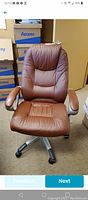Front view of brown office chair showing padded seat, backrest with stitched details, padded armrests, and caster wheels on metal base.