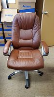 Front view showing brown leather upholstery, padded armrests, seat, and backrest with quilting detail.