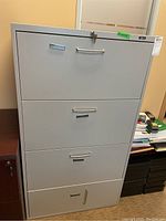Front view of metal filing cabinet with four drawers. Bottom handle damaged.