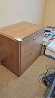Side angled view of 2 drawer filing cabinet showing wood grain finish and handle details.
