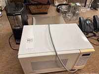 White Goldstar microwave model GSX-5108-M with digital keypad and display, placed on carpeted floor.
