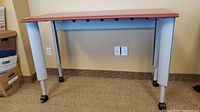 Front view of the office table showing wood top and metal legs on wheels.