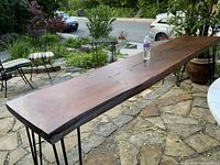 Full length view of the live edge table on stone patio with water bottle for scale