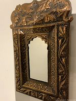 Close-up angled view showing embossed copper floral patterns on the mirror frame.