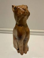 Front and side views of vintage Mid-Century Modern wooden dog sculpture showing natural wood grain and carved facial and body details.