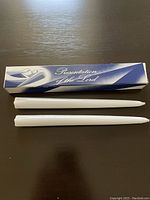 Two white wax taper candles in box with Presentation of the Lord design