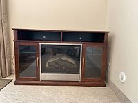 Front view of Kingsville credenza with two glass side doors, central electric fireplace insert, and two open top compartments.