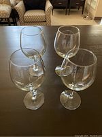 Four stemmed wine glasses and two stemless wine glasses arranged on a dark surface