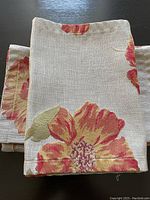 Close-up of folded floral table runner showing fabric texture and flower detail.