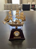 Miniature sailing ship in gold mounted on dark wood plaque with clock and brass nameplate 'Valletta - Malta'