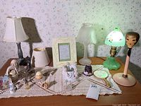 Full view of dresser top showing lamps, framed print, miniatures, thimbles, and assorted knick knacks on crocheted doily