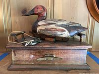 Front view showing wooden duck decoy mounted on wood display box with drawer and attached anchor