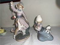 Wide shot of the two Lladro animal themed figurines on a table.