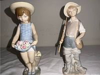 Both boy and girl Lladro figurines displayed side by side on white surface, showing front view and details of figures.