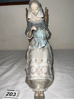 Front view of Lladro figurine showing woman sitting on the chair with sewing embroidery hoop.