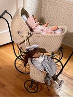 Two vintage dolls resting in a wicker carriage and a smaller wicker stroller. Dolls measure about 16 inches tall. Carriage dimensions 14x28x29 inches, stroller 10x16x14 inches.