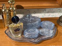 Full view of powder blue glass vanity set on scalloped tray with Shalimar perfume bottle and two gold-tone atomizers