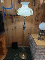 Full view of the floor lamp showing height and overall design including metal base and painted glass globe.