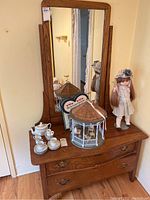 Full view of wood dresser with attached tilting mirror and various items on top (not included). Shows dresser style, hardware, and condition.