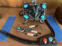Photo showing all three items: belt buckle, bolo tie, and pendant arranged on wooden surface